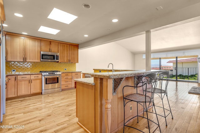 3467 Skyline Blvd, Reno, NV 89509 - kitchen with appliances with stainless steel finishes, light wood-type flooring, a kitchen bar, decorative backsplash, and recessed lighting