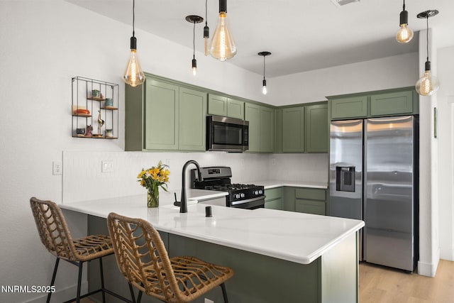 3621 Pimlico St, Reno, NV 89512 - kitchen with stainless steel appliances, green cabinets, a peninsula, light countertops, and a kitchen breakfast bar