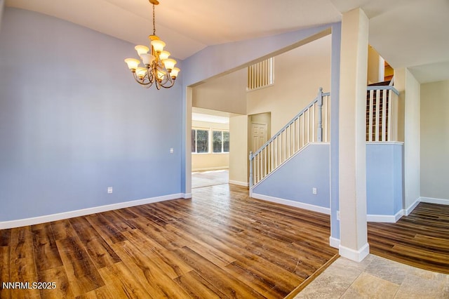 10595 Baton Ct, Reno, NV 89521 - empty room with stairway, a chandelier, wood finished floors, vaulted ceiling, and baseboards