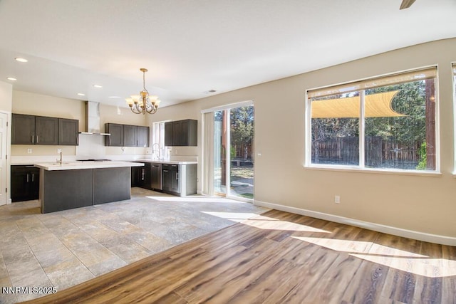 10595 Baton Ct, Reno, NV 89521 - kitchen featuring wall chimney exhaust hood, a chandelier, light countertops, baseboards, and recessed lighting