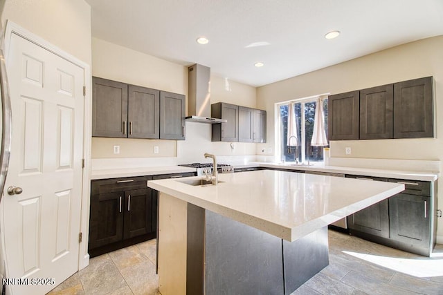 10595 Baton Ct, Reno, NV 89521 - kitchen featuring wall chimney exhaust hood, a sink, a kitchen island with sink, recessed lighting, and dark brown cabinetry
