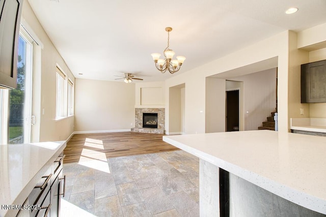 10595 Baton Ct, Reno, NV 89521 - unfurnished living room with a chandelier, a ceiling fan, stairway, a fireplace with raised hearth, and baseboards