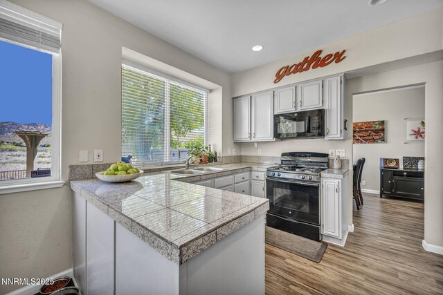 3250 Eaglewood Dr, Reno, NV 89502 - kitchen featuring range with gas stovetop, tile countertops, black microwave, a sink, and wood finished floors