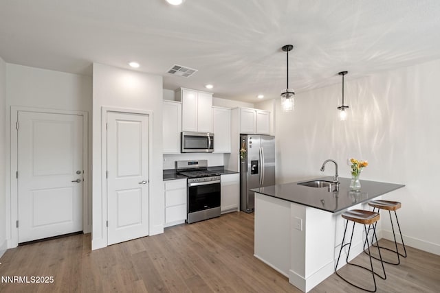 1440 Solitude Trl, Reno, NV 89523 - kitchen featuring appliances with stainless steel finishes, a sink, dark countertops, a kitchen bar, and white cabinetry
