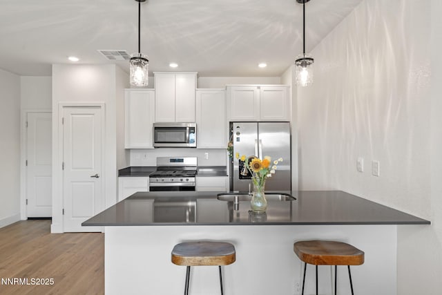 1440 Solitude Trl, Reno, NV 89523 - kitchen featuring stainless steel appliances, dark countertops, white cabinetry, wood finished floors, and a kitchen breakfast bar