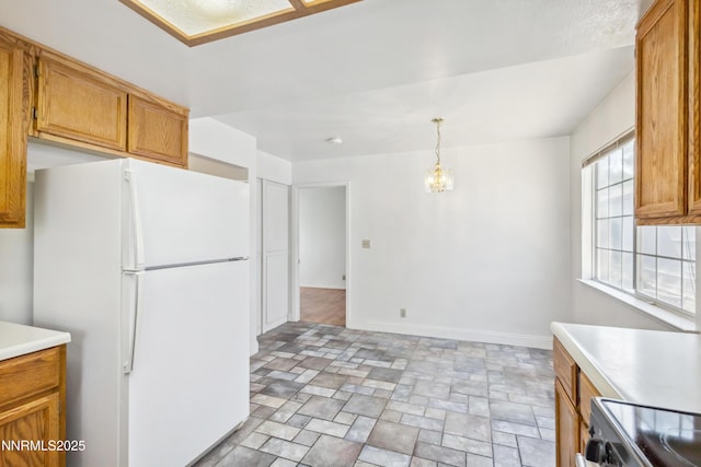 7554 Whimbleton Way, Reno, NV 89511 - kitchen featuring freestanding refrigerator, stone finish flooring, light countertops, brown cabinets, and baseboards