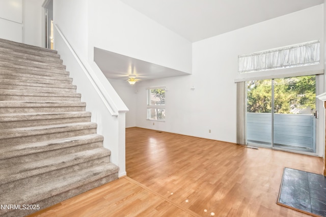 7554 Whimbleton Way, Reno, NV 89511 - unfurnished living room with stairs, wood finished floors, a ceiling fan, and a towering ceiling