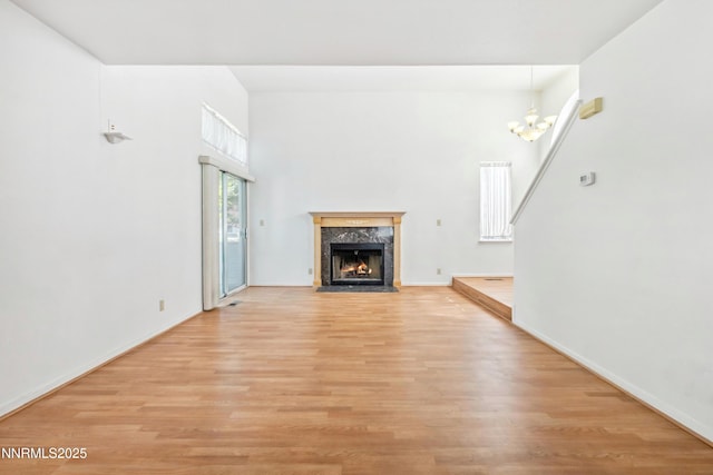 7554 Whimbleton Way, Reno, NV 89511 - unfurnished living room with light wood finished floors, a chandelier, a fireplace, a towering ceiling, and baseboards