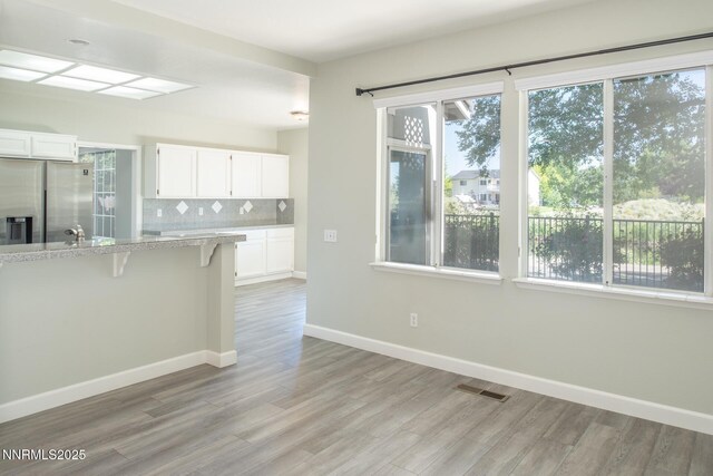 4734 Tierrapark Ct, Reno, NV 89502 - kitchen with stainless steel fridge with ice dispenser, light wood-type flooring, white cabinets, and a kitchen breakfast bar