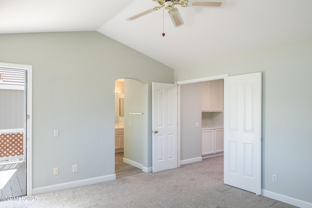 4734 Tierrapark Ct, Reno, NV 89502 - unfurnished bedroom with arched walkways, vaulted ceiling, light carpet, ensuite bath, and a ceiling fan