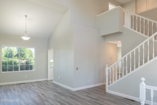 4734 Tierrapark Ct, Reno, NV 89502 - unfurnished living room featuring high vaulted ceiling, wood finished floors, and stairway