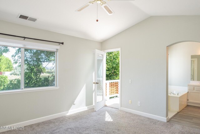 4734 Tierrapark Ct, Reno, NV 89502 - unfurnished bedroom featuring multiple windows, arched walkways, vaulted ceiling, access to exterior, and ensuite bath
