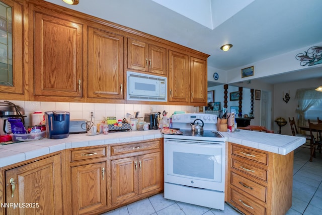 1650 Trabert Way, Sparks, NV 89431 - kitchen with white appliances, a peninsula, light tile patterned floors, brown cabinetry, and decorative backsplash
