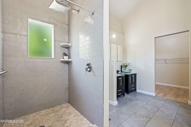 105 Rodeo Dr, Reno, NV 89508 - bathroom featuring tiled shower, vanity, a walk in closet, lofted ceiling, and tile patterned floors