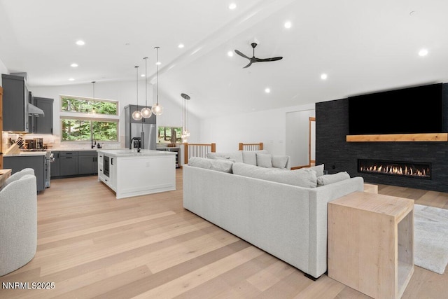 1877 Normuk St, South Lake Tahoe, CA 96150 - living room with light wood-style flooring, a glass covered fireplace, a ceiling fan, beamed ceiling, and recessed lighting