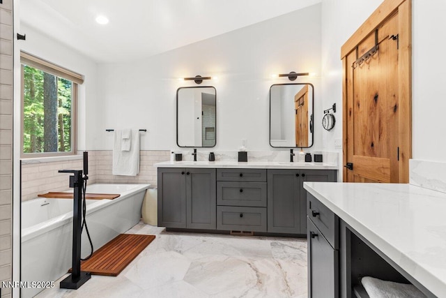 1877 Normuk St, South Lake Tahoe, CA 96150 - bathroom with marble finish floors, double vanity, a freestanding bath, tile walls, and a wainscoted wall