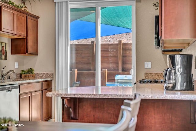 3678 Hollywood Park Dr, Reno, NV 89512 - kitchen with dishwasher, a sink, light stone counters, brown cabinetry, and a textured wall