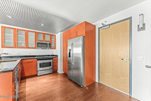 255 N Sierra St Unit 1709, Reno, NV 89501 - kitchen with stainless steel appliances, wood finished floors, dark countertops, glass insert cabinets, and brown cabinetry