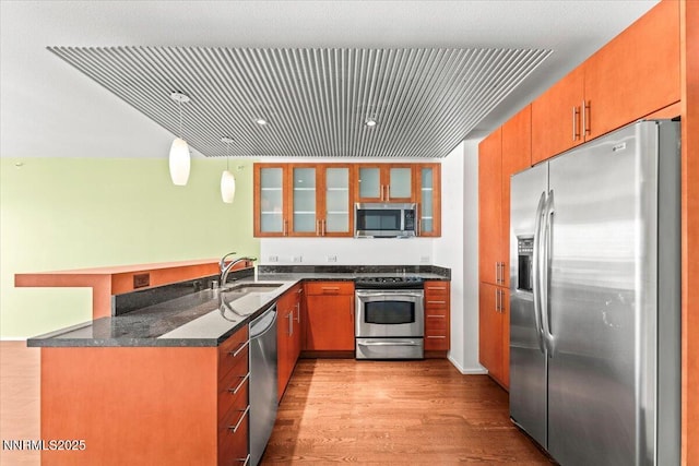 255 N Sierra St Unit 1709, Reno, NV 89501 - kitchen with appliances with stainless steel finishes, a peninsula, light wood-style floors, glass insert cabinets, and hanging light fixtures