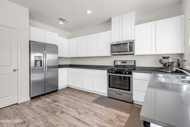 503 Astraea Trl, Reno, NV 89506 - kitchen with appliances with stainless steel finishes, a sink, dark countertops, light wood finished floors, and white cabinets