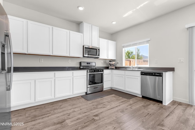 503 Astraea Trl, Reno, NV 89506 - kitchen featuring appliances with stainless steel finishes, dark countertops, white cabinets, light wood-type flooring, and recessed lighting