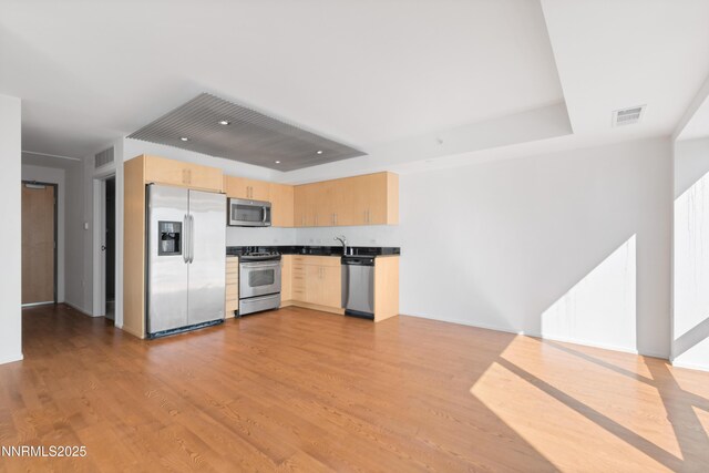 255 N Sierra St Unit 1210, Reno, NV 89501 - kitchen featuring stainless steel appliances, light brown cabinets, light wood-style floors, dark countertops, and a raised ceiling