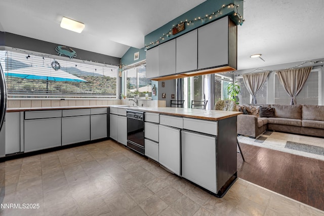 7090 Peppermint Dr, Reno, NV 89506 - kitchen featuring black dishwasher, lofted ceiling, a peninsula, open floor plan, and white cabinets
