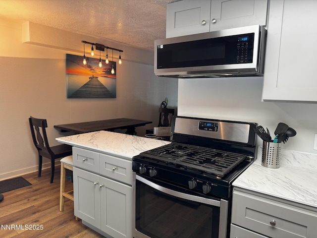 810 Alder Ave Unit 61, Incline Village, NV 89451 - kitchen featuring appliances with stainless steel finishes, wood finished floors, a textured ceiling, a peninsula, and light stone countertops