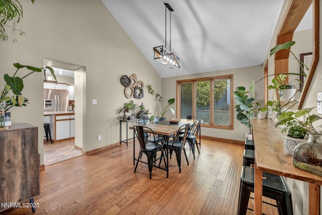 5595 Kluncy Canyon Rd, Winnemucca, NV 89445 - dining space with light wood-type flooring, high vaulted ceiling, and baseboards
