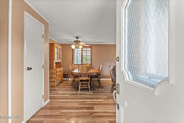 4415 Leche Way, Reno, NV 89502 - dining area with light wood-style floors, a ceiling fan, crown molding, a textured ceiling, and baseboards