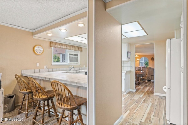 4415 Leche Way, Reno, NV 89502 - kitchen featuring freestanding refrigerator, ornamental molding, tile counters, plenty of natural light, and a kitchen bar
