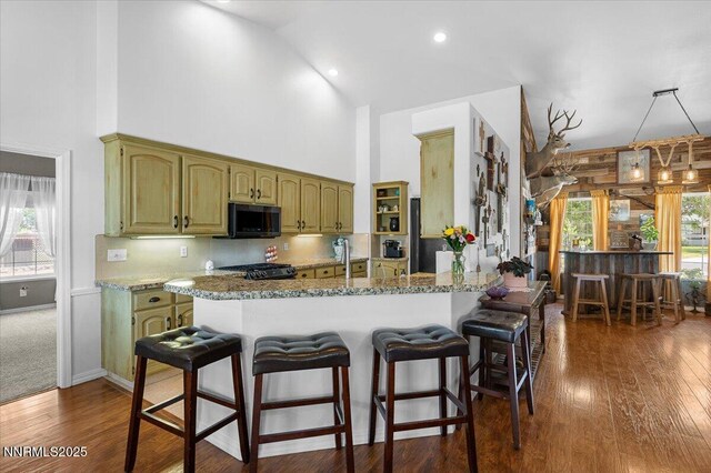 1055 Golden Park Way, Fallon, NV 89406 - kitchen with black microwave, gas stove, high vaulted ceiling, a kitchen bar, and dark wood finished floors