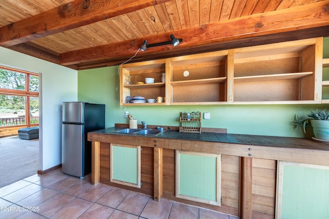 15118 N Timberline Dr, Reno, NV 89511 - kitchen featuring freestanding refrigerator, light tile patterned floors, a sink, light colored carpet, and wooden ceiling with exposed beams
