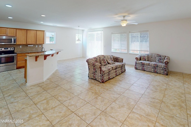 1509 Lasso Ln, Gardnerville, NV 89410 - kitchen with appliances with stainless steel finishes, a kitchen bar, decorative backsplash, ceiling fan, and recessed lighting