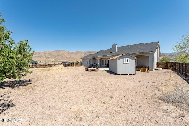 4945 Broken Spur Rd, Reno, NV 89510 - back of property with a fenced backyard, a mountain view, and a chimney