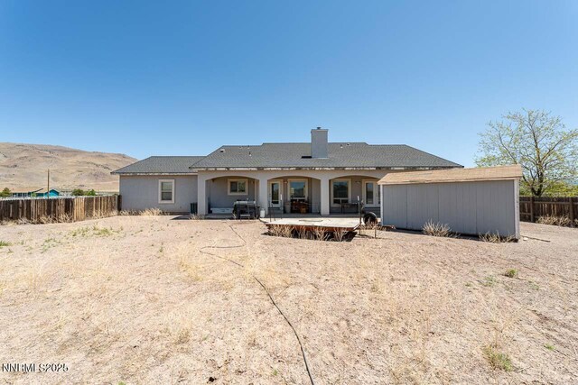 4945 Broken Spur Rd, Reno, NV 89510 - back of property with a patio, a chimney, a mountain view, and an outdoor structure