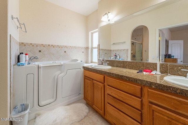 4945 Broken Spur Rd, Reno, NV 89510 - bathroom featuring a stall shower, a garden tub, double vanity, tile patterned flooring, and tile walls