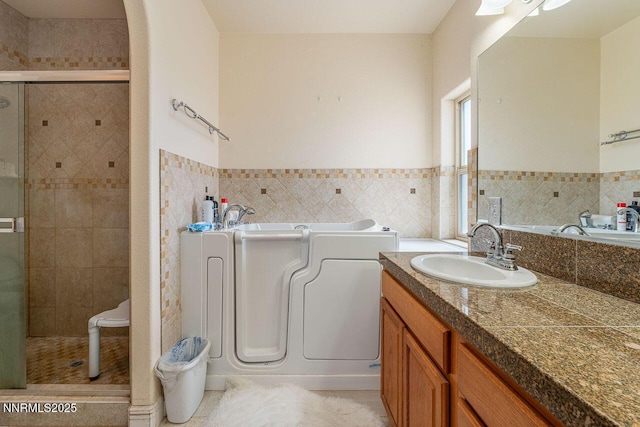 4945 Broken Spur Rd, Reno, NV 89510 - full bathroom featuring tile walls, a bath, a stall shower, vanity, and wainscoting
