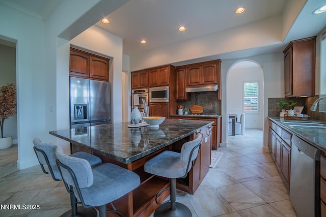 8270 Antler Pointe Ct, Reno, NV 89523 - kitchen with appliances with stainless steel finishes, under cabinet range hood, arched walkways, backsplash, and a breakfast bar area