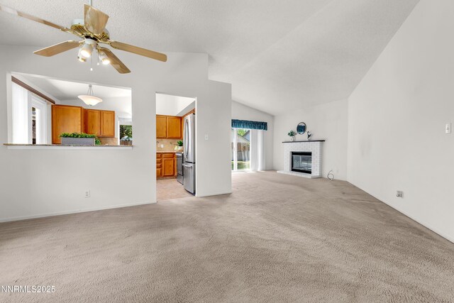 3353 Alpland Ln, Sparks, NV 89434 - unfurnished living room featuring light colored carpet, vaulted ceiling, a brick fireplace, and a ceiling fan