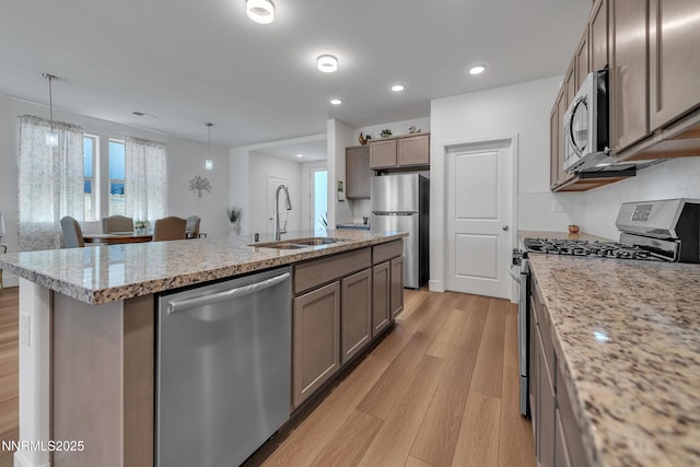 353 Radiant Dr, Carson City, NV 89705 - kitchen with stainless steel appliances, a sink, light wood-style floors, an island with sink, and tasteful backsplash