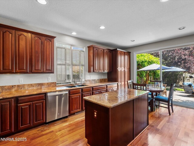 1121 Sageberry Ct, Reno, NV 89509 - kitchen with dishwasher, a sink, light wood-style flooring, light stone counters, and a center island