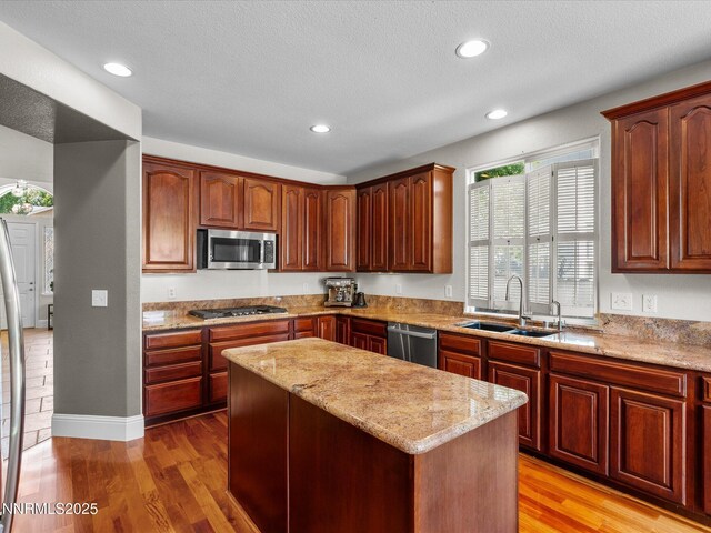 1121 Sageberry Ct, Reno, NV 89509 - kitchen featuring stainless steel appliances, a sink, light wood-type flooring, a kitchen island, and light stone counters