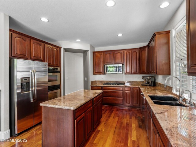 1121 Sageberry Ct, Reno, NV 89509 - kitchen featuring appliances with stainless steel finishes, a sink, dark wood finished floors, light stone counters, and a center island