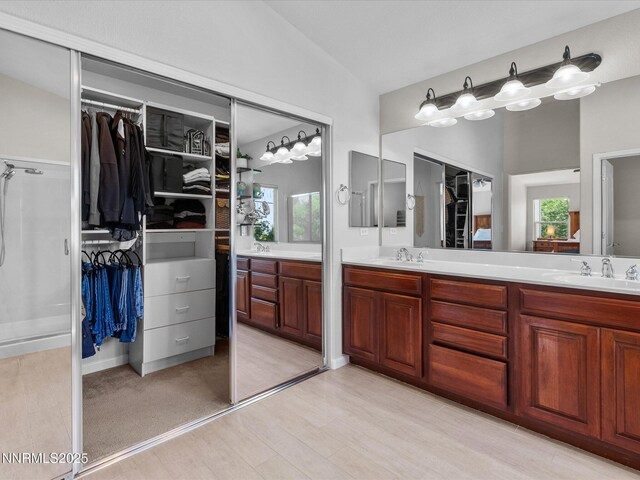 1121 Sageberry Ct, Reno, NV 89509 - bathroom featuring double vanity, vaulted ceiling, a spacious closet, wood finished floors, and healthy amount of natural light