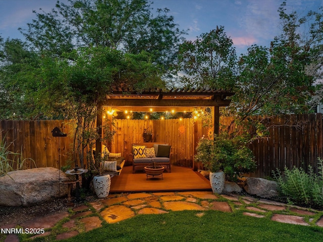 1121 Sageberry Ct, Reno, NV 89509 - patio terrace at dusk with a wooden deck, a fenced backyard, an outdoor living space with a fire pit, and a pergola