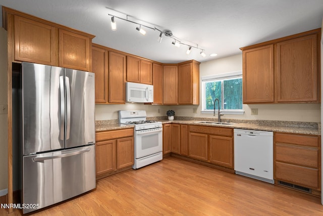 423 Bath St, Carson City, NV 89703 - kitchen with white appliances, brown cabinets, light wood-type flooring, and light stone countertops