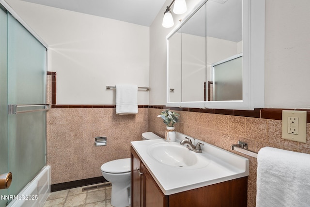 423 Bath St, Carson City, NV 89703 - full bathroom featuring vanity, tile walls, bath / shower combo with glass door, and wainscoting
