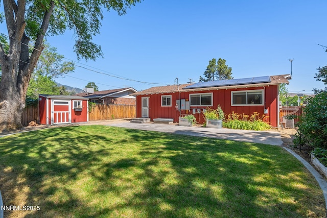 423 Bath St, Carson City, NV 89703 - back of property featuring board and batten siding, roof mounted solar panels, a storage shed, a patio, and a fenced backyard