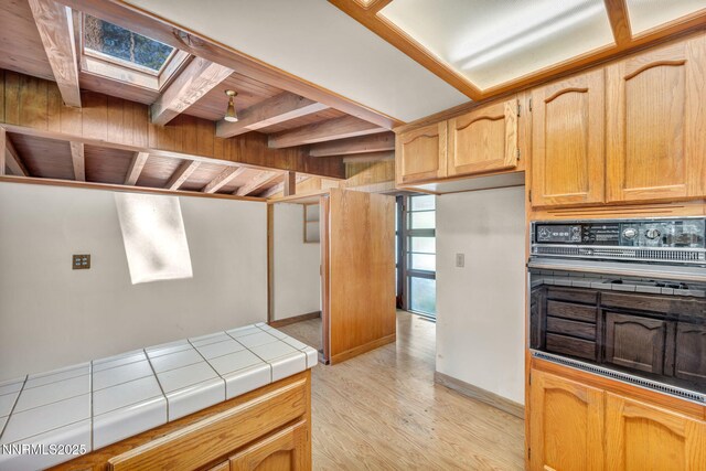 161 Willow Dr, Zephyr Cove, NV 89448 - kitchen with black oven, a skylight, light wood-style floors, tile counters, and backsplash